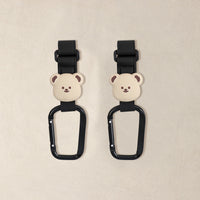 ベージュのクマのモチーフが際立つ、ブラックPUレザーのペットカートフック2個セット。シンプルで落ち着いた配色の、左右ペアで使用する商品。